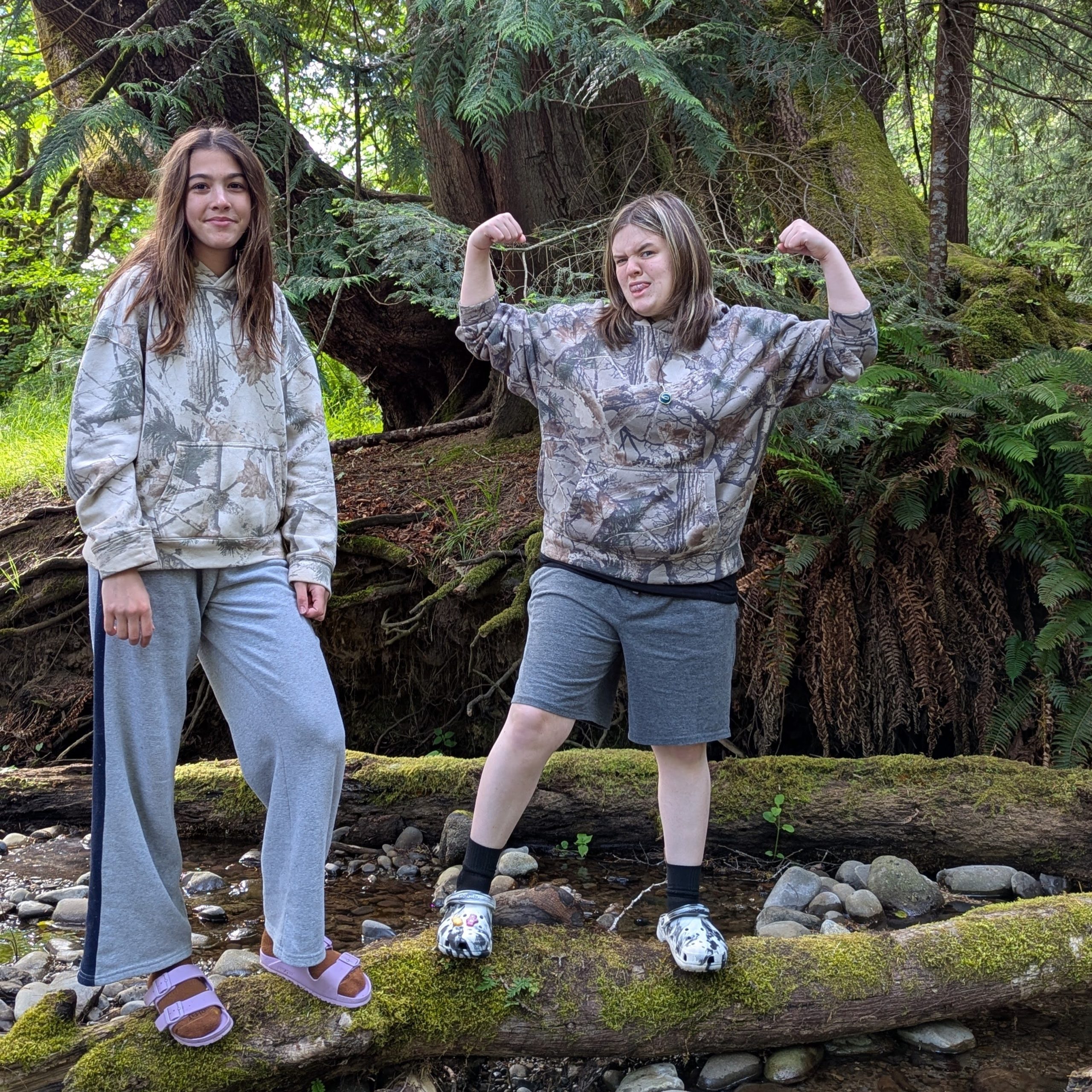 Two middle school students pose on a log in the forest